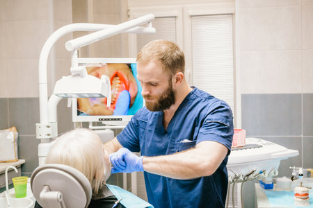 An elderly woman at the reception of a young male dentist. Fitting of the false jaw.の写真素材