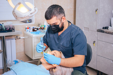 A girl at the reception of a male dentist in a dental chair, with her mouth open during an injection of painkillers.の写真素材