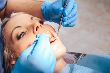 A girl at the reception of a male dentist in a dental chair, with her mouth open during the procedure.の写真素材