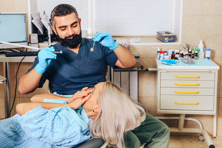 A frightened blonde girl at a reception at a cheerful, smiling dentist.の写真素材