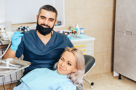 A frightened blonde girl at a reception at a cheerful, smiling dentist.の写真素材
