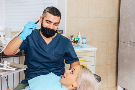 A frightened blonde girl at a reception at a cheerful, smiling dentist.の写真素材