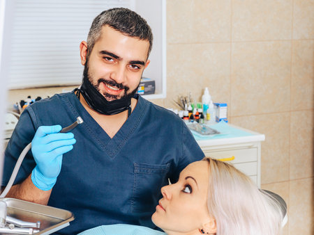 A frightened blonde girl at a reception at a cheerful, smiling dentist.の写真素材
