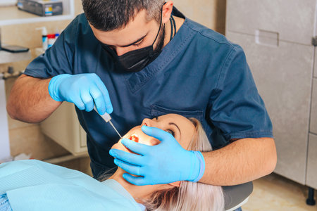A girl at the reception of a male dentist in a dental chair, with her mouth open during the procedure.の写真素材