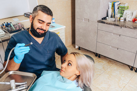 A frightened blonde girl at a reception at a cheerful, smiling dentist.の写真素材
