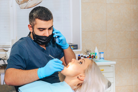 The dentist talks on the phone during the examination of the patient.の写真素材