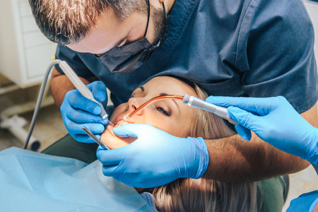 A girl at the reception of a male dentist in a dental chair, with her mouth open during the procedure.の写真素材