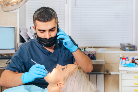 The dentist talks on the phone during the examination of the patient.の写真素材