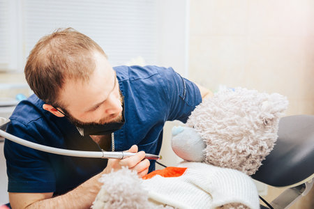 Dentist a man with a teddy bear in the form of a patient in a chair.の写真素材