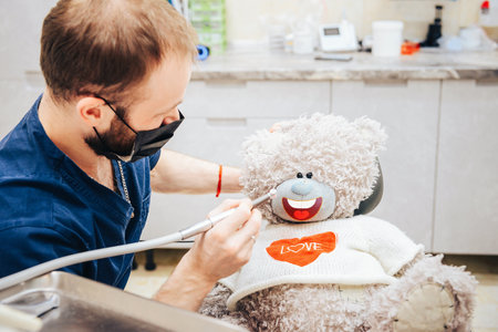 Dentist a man with a teddy bear in the form of a patient in a chair.の写真素材