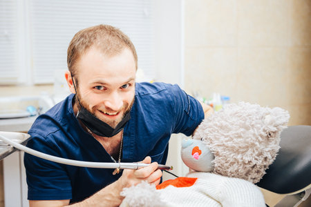 Dentist a man with a teddy bear in the form of a patient in a chair.の写真素材