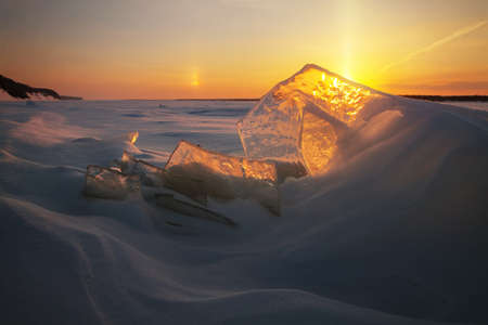 setting sun shines through the ice on the river bankの写真素材