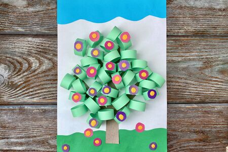 3D applique of colored paper, volume, spring tree with flowers, on a wooden background, handmade.の写真素材