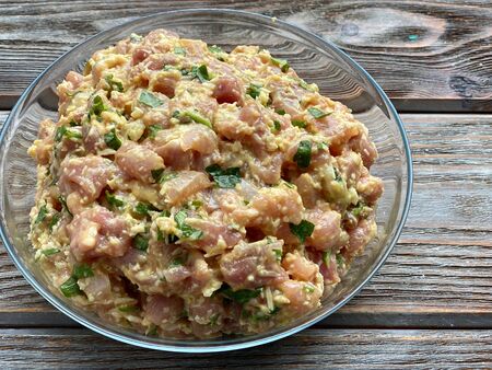 chopped chicken meat with cheese and herbs, for cooking cutlets, on a wooden table.の写真素材