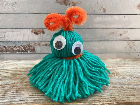 green monster made of yarn on a wooden background, childrens creativity.の写真素材