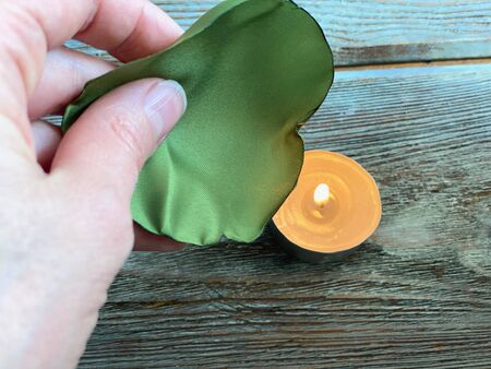 Green petal made of fabric, burn on a candle flame, flower needlework.の写真素材