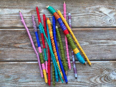 a set of dry sticks is wrapped with colored yarn on a wooden background.の写真素材