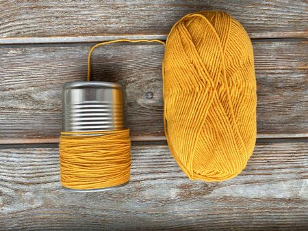 A can wrapped in yellow thread on a wooden background is ready to become a bee. Childrens crafts step by step.の写真素材