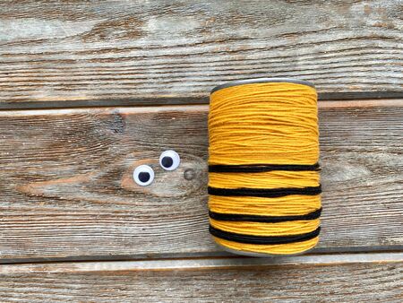 tin can wrapped in yellow thread, next to plastic eyes, for bees, childrens creative.の写真素材