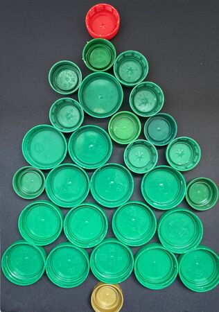 Christmas tree made of plastic covers on a black background, art craft.の写真素材