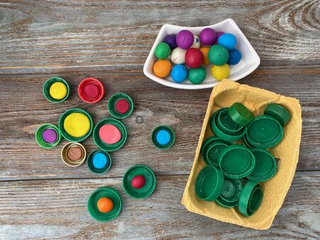 Multi-colored plasticine and green plastic lids on a wooden background, for childrens crafts.の写真素材