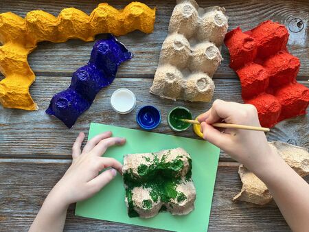Childrens hands paint the egg box with different colorsの写真素材