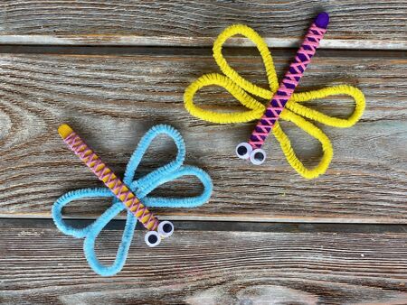 Two dragonflies, childrens crafts from pipe cleaners and wooden sticks with yarn.の写真素材