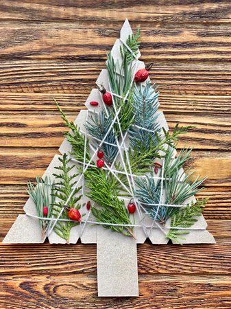 Floral Christmas tree made of cardboard and fir branches, kids craft.の写真素材