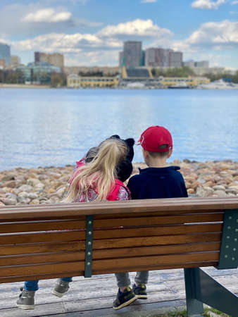 Small children sit on a bench in the park, near the riverのeditorial素材