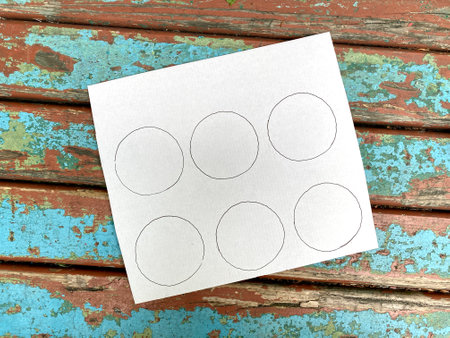 On the cardboard, six circles are drawn with a felt-tip pen on a wooden background.の写真素材