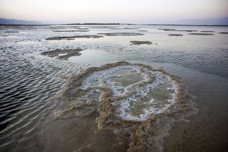 The water of the dead sea with salty paths at sunsetの写真素材