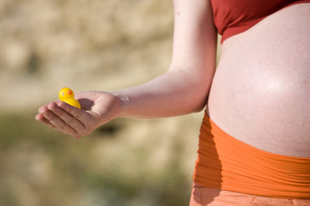 Belly of a pregnant women with a duck toy in her handの写真素材