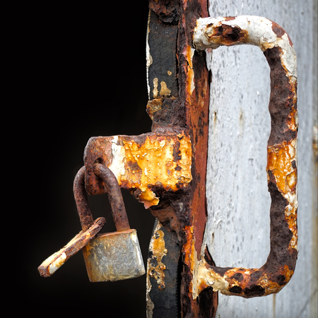 Old lock weighing on rusty door opens voidの写真素材
