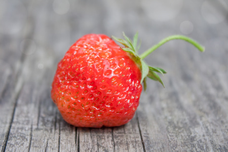 A fresh ripe strawberry on an old wooden surface  It has just been harvested and is very appetizing の写真素材
