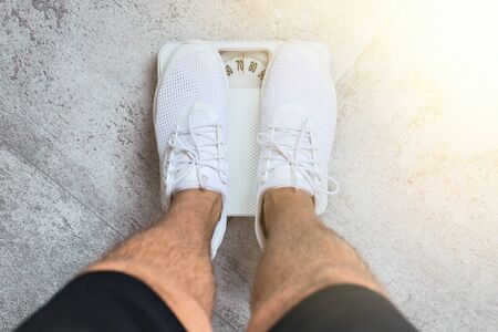 Weighing. Men feet standing on weigh scales.の写真素材