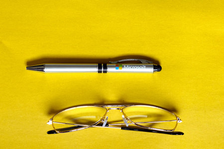 Kaliningrad, RUSSIA - OCTOBER 26, 2019: pen with Microsoft logo and glasses on yellow paper on a black table.のeditorial素材