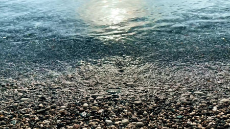 A minimalistic close-up shot from the beach to the sea waves with pebbles in the foregroundの写真素材