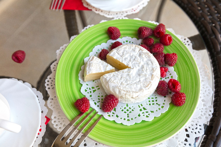 Soft white cheese and raspberries on a tableの写真素材