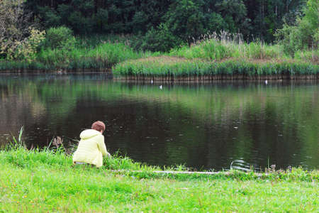 woman sitting by lake landscape relax calm water reflectionの写真素材