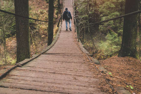 photographer traveler on a suspension bridge in forest wild extreme journeyの写真素材