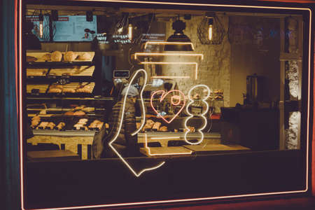 neon coffee sign on the street of the city hand holds a hot mugの写真素材
