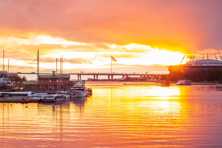 Yacht parking and stadium arena St. Petersburg with flagpole .dynamic movement of clouds. sunset .concept change of weather .orange and pink colors.