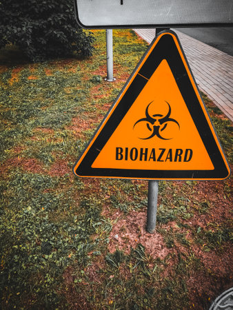 Sign biohazard of biological contamination of danger triangular shape, on grass contaminated soil.の写真素材