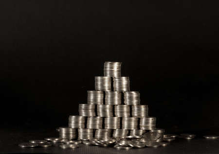 Pyramid from silver coins on a black background. A loose of coins.の写真素材