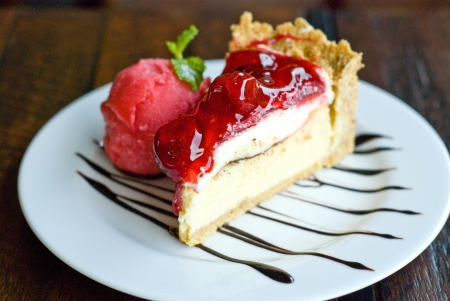 horizon view of portion of strawbery cheese cake and sreawberry ice-creme on white plate topping with chocolate sauceの写真素材