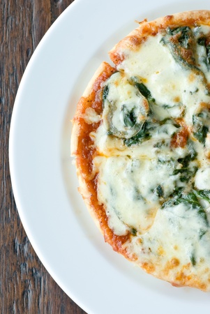 directly top view of spinach pizza on white plate in half round shapeの写真素材