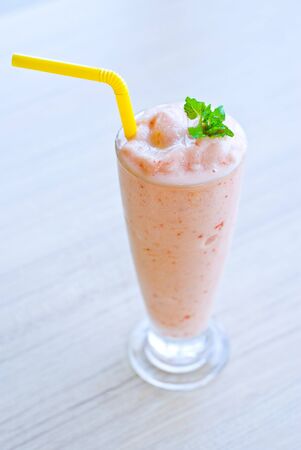glass of strawberry smoothie top with pepper mint on tableの写真素材