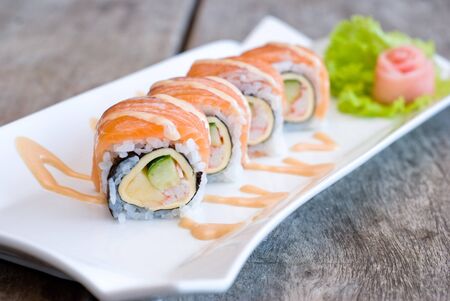 salmon sashimi roll on white plate topping with cream sauceの写真素材