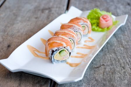 salmon sashimi roll on white plate topping with cream sauceの写真素材