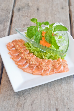 salmon sashimi topping with spicy sauce and fresh mix vegetableの写真素材